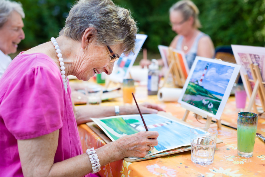 Seniors are enjoying a group painting session outdoors